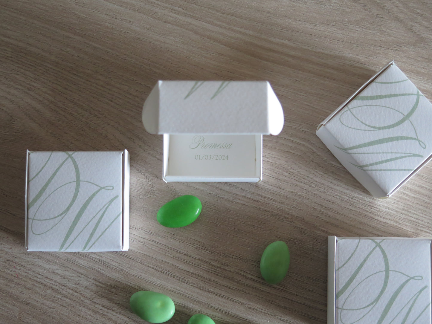 Scatole porta confetti promessa matrimonio verde salvia disposte elegantemente design minimal
