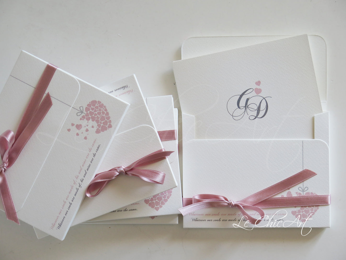 Vista dettaglio partecipazioni matrimonio rosa antico con decorazioni cuore e chiusura nastro