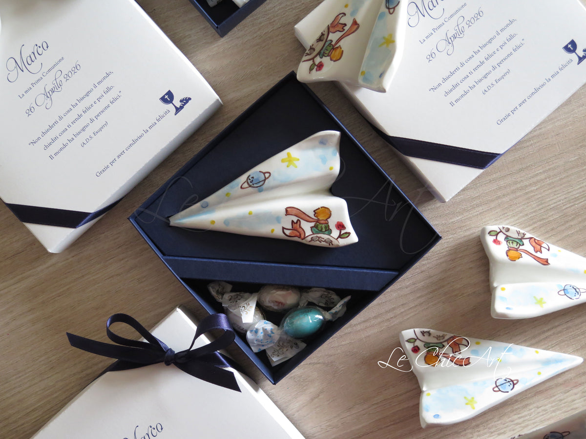Bomboniera aeroplano con Piccolo Principe dipinto a mano, scatola blu notte aperta con confetti e coperchio personalizzato con calice e vino stampati.