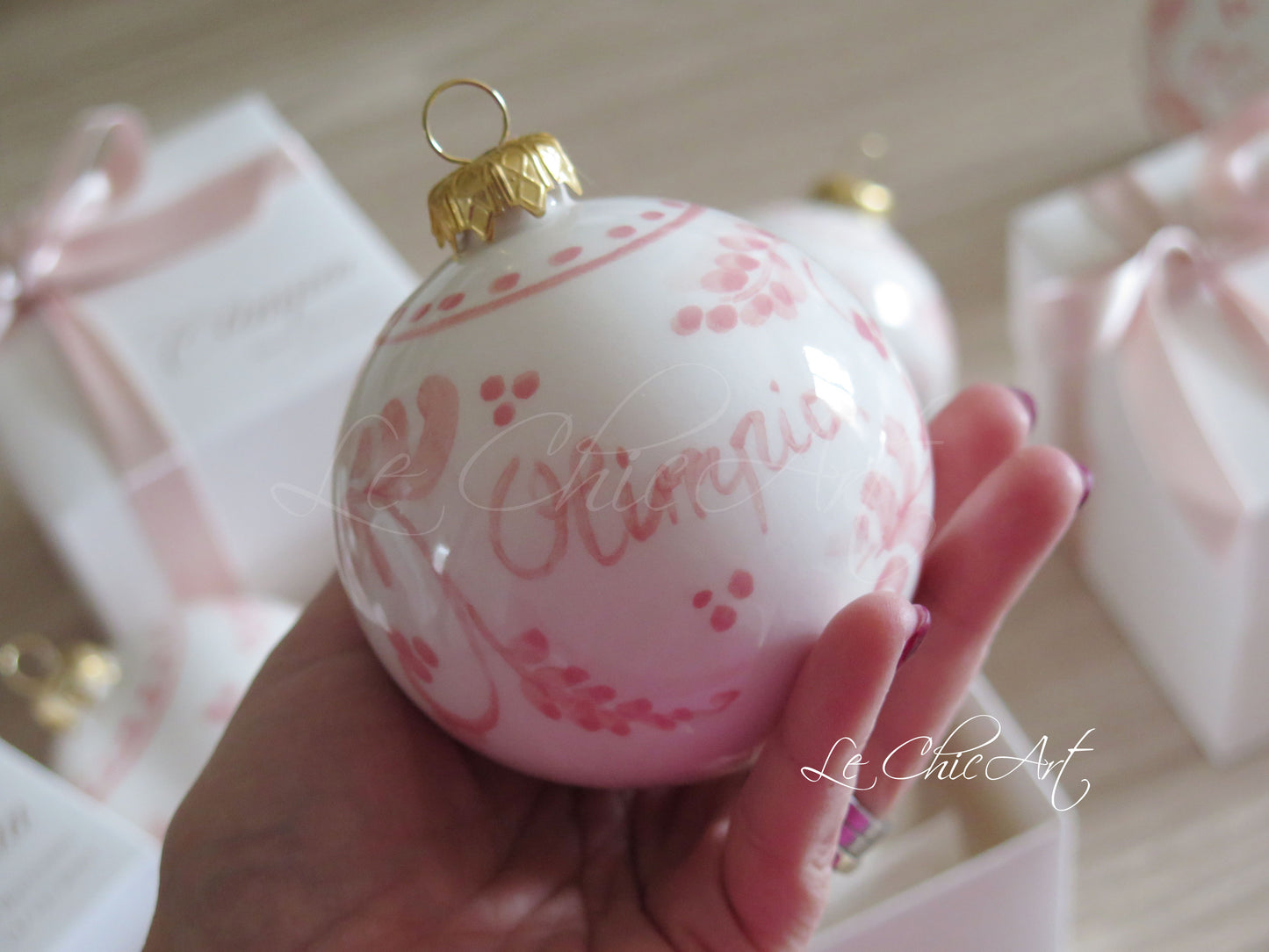 Dettaglio dipinto floreale rosa cipria e rosa antico su palla natalizia in ceramica, pennellate artistiche sfumate a mano con effetti astratti