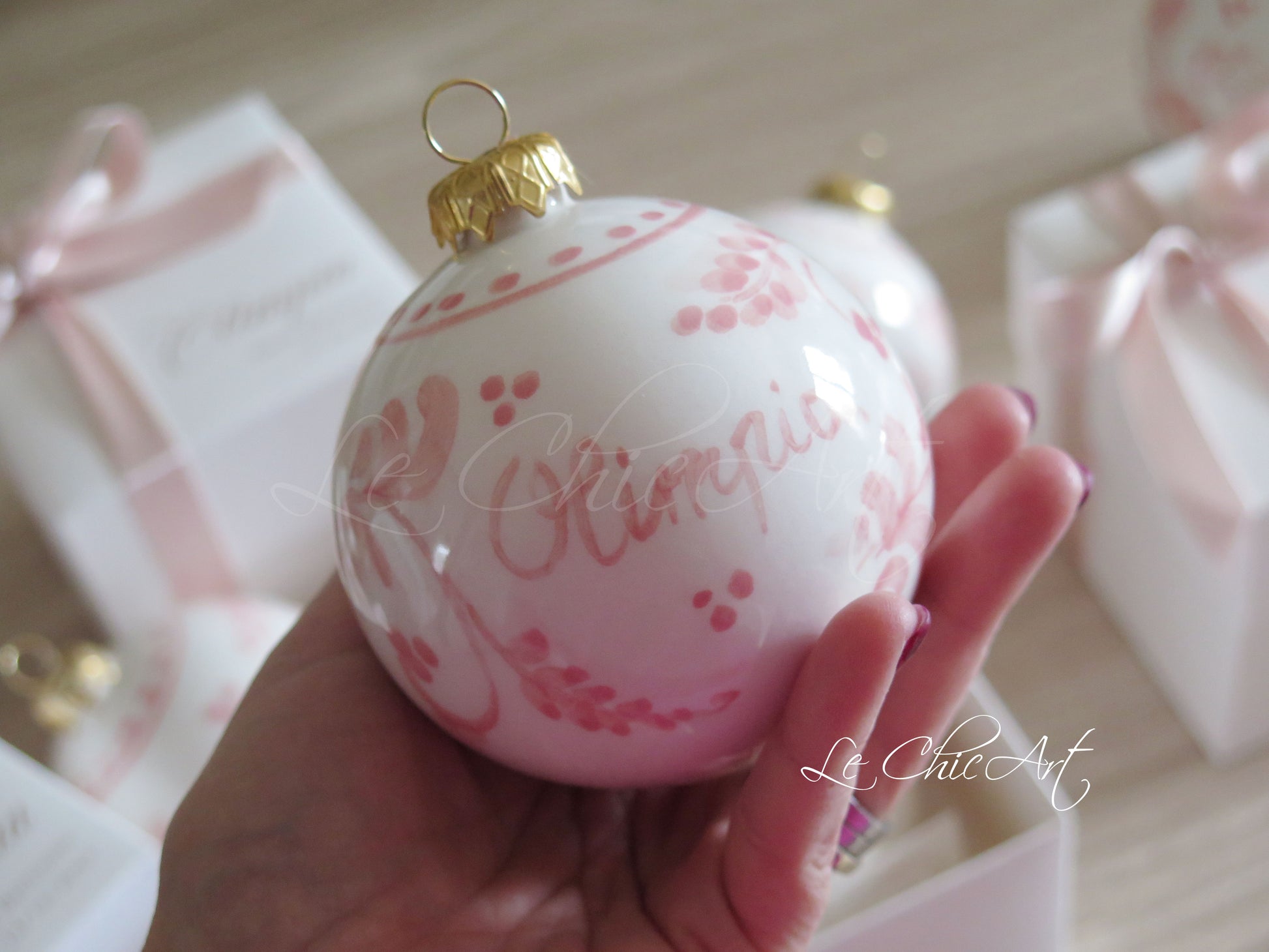 Dettaglio dipinto floreale rosa cipria e rosa antico su palla natalizia in ceramica, pennellate artistiche sfumate a mano con effetti astratti