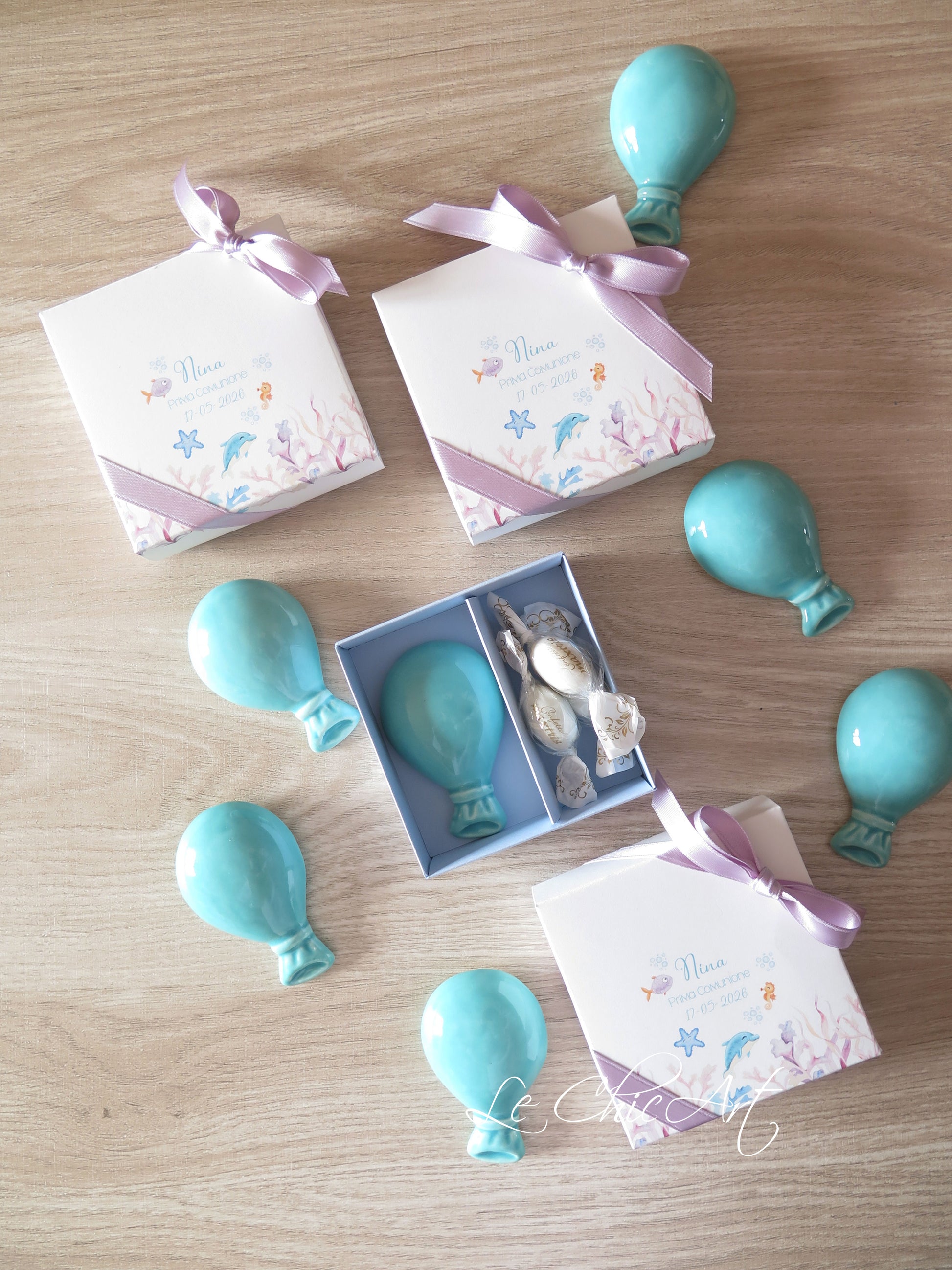 Dettaglio palloncino ceramica tiffany con calamita tema mare, fondo contenitore azzurro polvere e nastro lilla, bomboniera personalizzata Made in Italy

