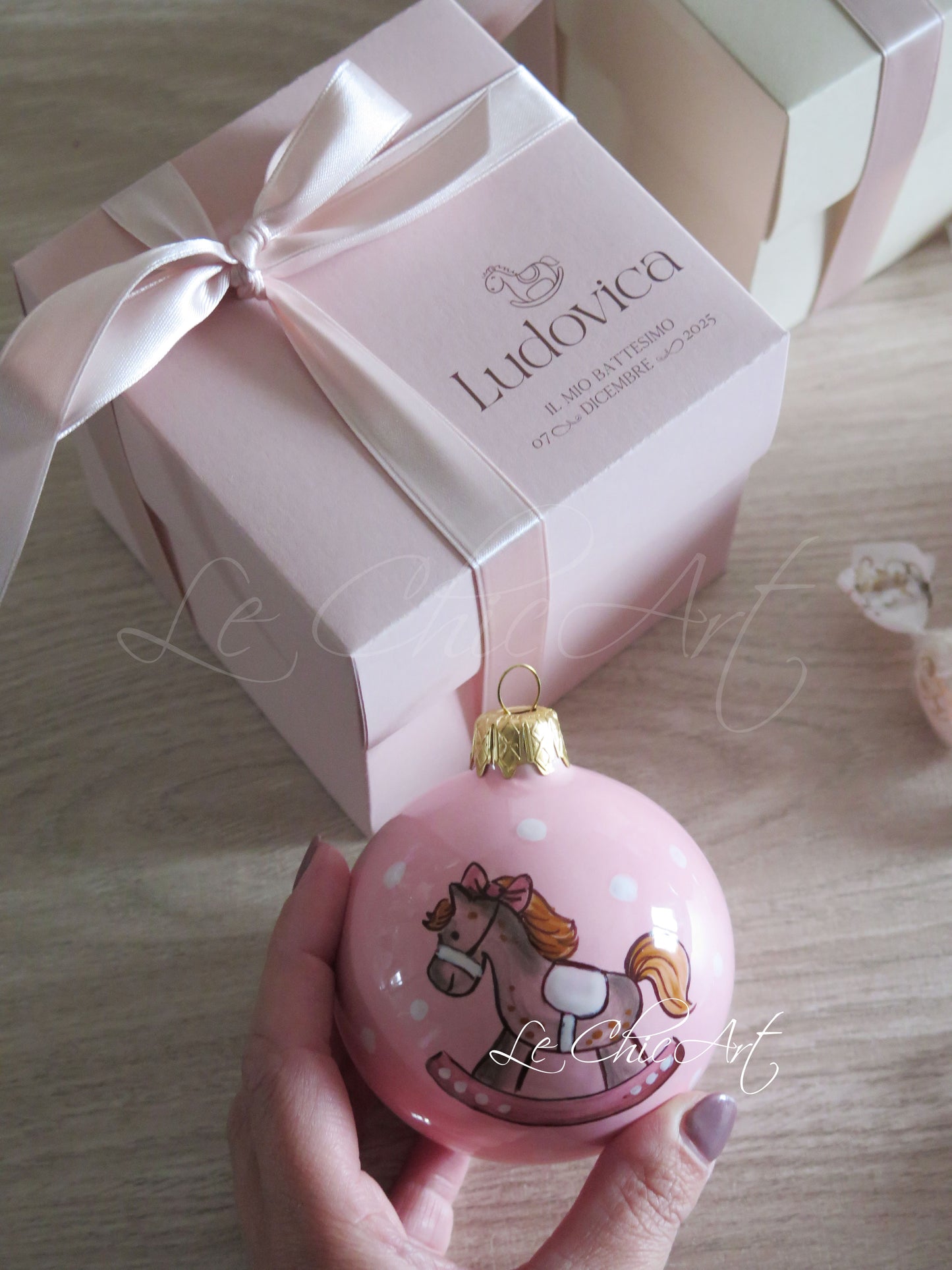 Dettaglio cavalluccio a dondolo dipinto a mano su palla natalizia rosa cipria, bomboniera battesimo in ceramica Made in Italy con decorazione artigianale