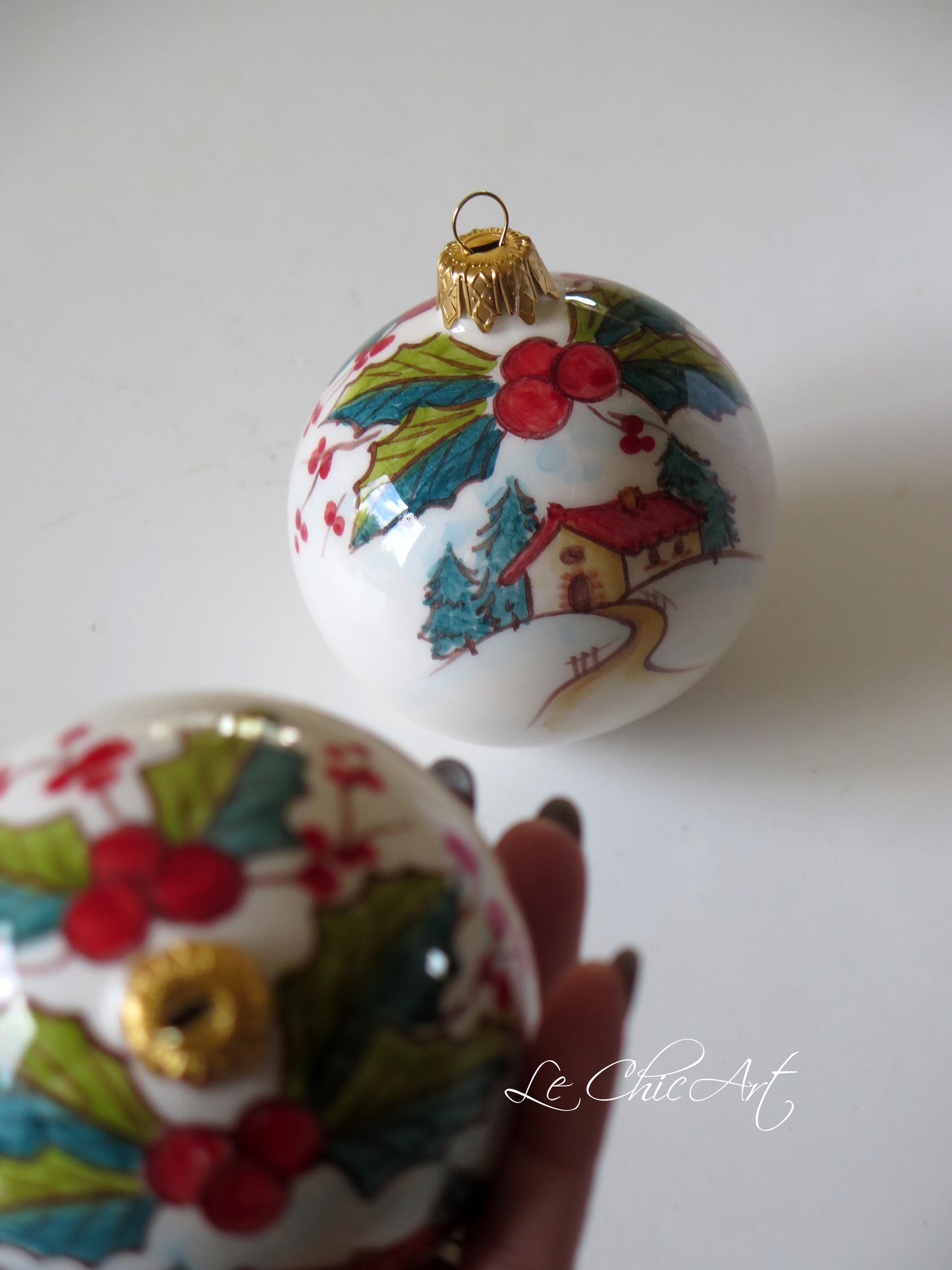 Dettaglio palla ceramica 8cm dipinta a mano con agrifogli bacche rosse e paesaggio innevato con casetta – bomboniera natale personalizzata luxury – Le ChicArt