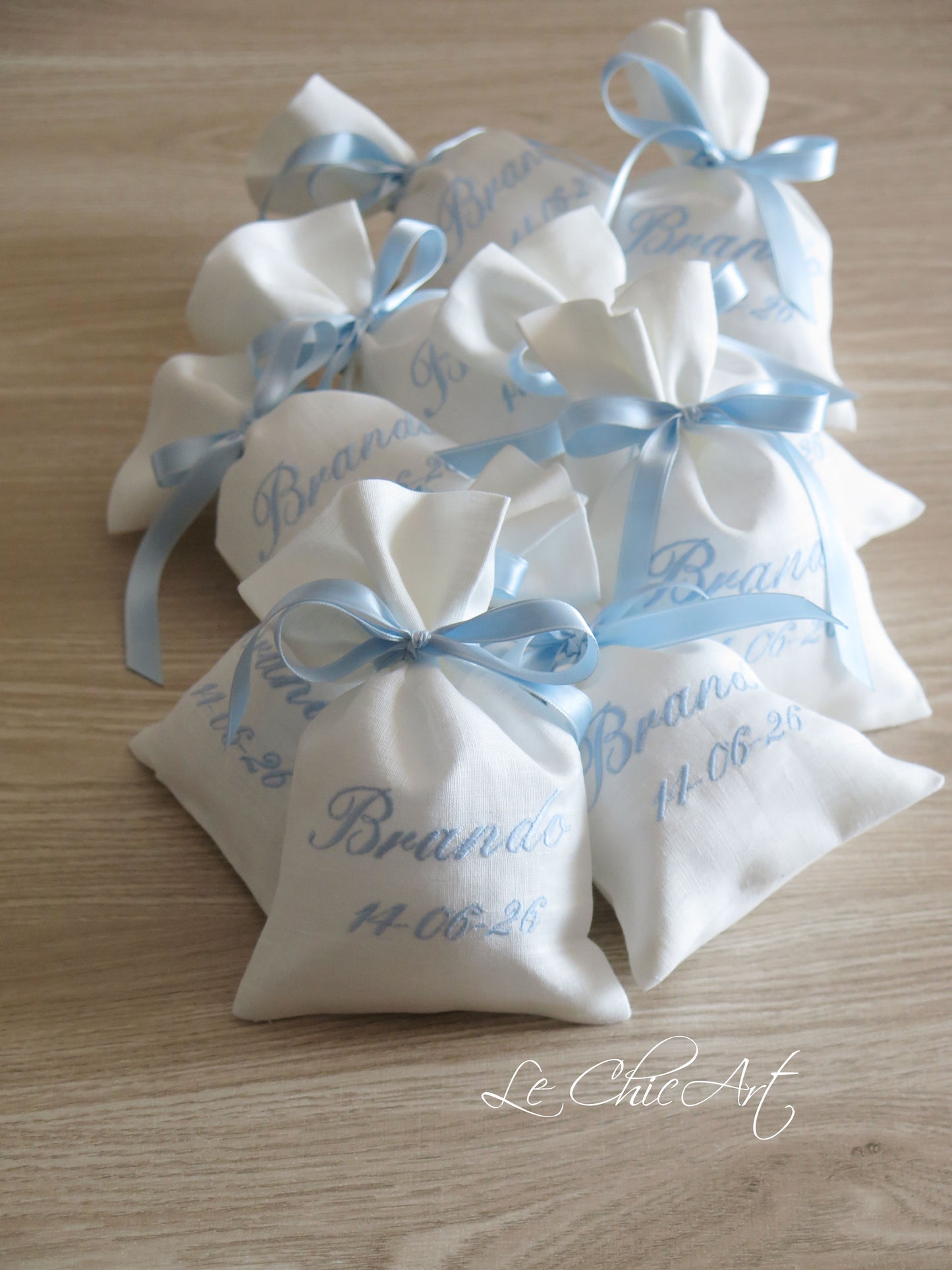 Dettaglio ricamo nome e data in corsiva azzurro polvere su sacchetto lino bianco naturale, bomboniera battesimo sartoriale artigianale Made in Italy Le ChicArt Lab